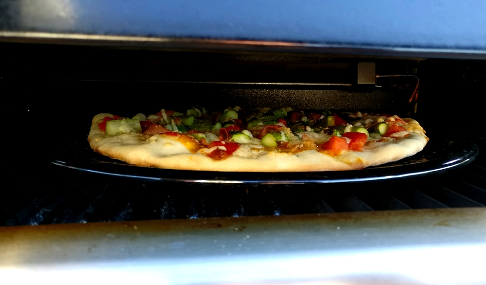 Ein Blick unter die Haube auf die Pizza mit grünem Spargel