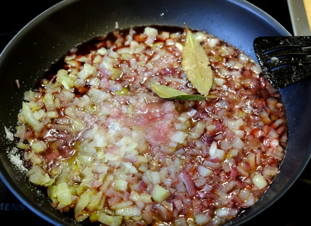 Die Zwiebeln werden mit Rotwein, Essig und Zucker aufgegossen und müssen dann für 20 Minuten einreduzieren.